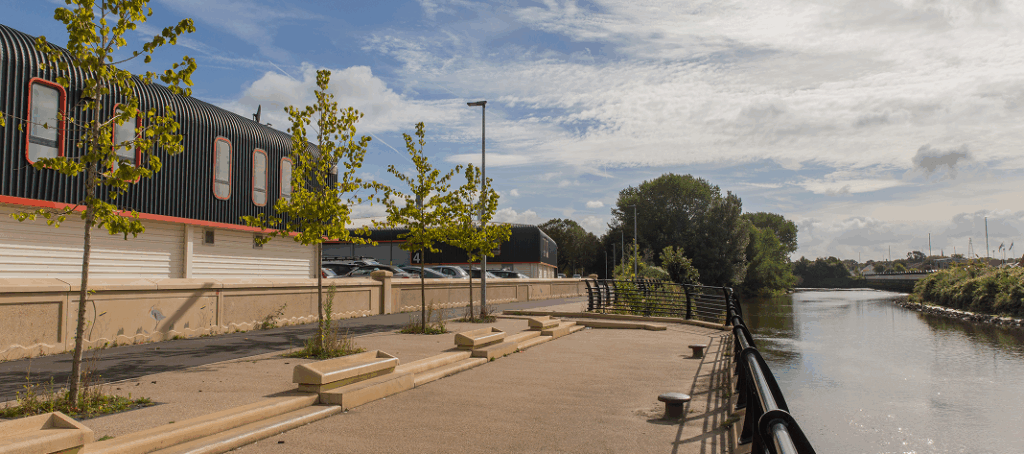 View of a modern riverside industrial site with newly planted trees